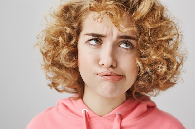 Funny curly-haired grimacing girl making faces and squinting