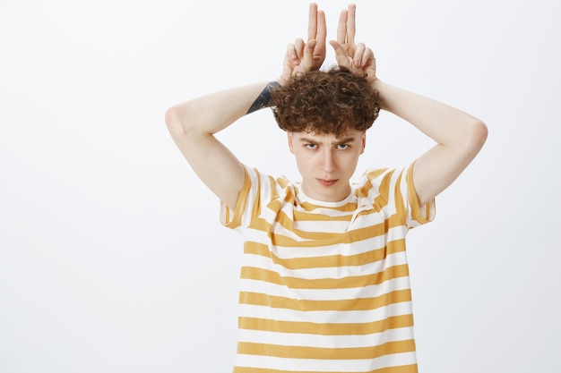 Free photo funny and cute teenage guy posing against the white wall