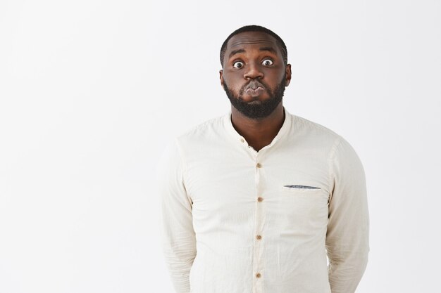 Funny and cute young guy posing against the white wall