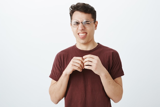 Free photo funny digusted young man in round glasses and red t-shirt