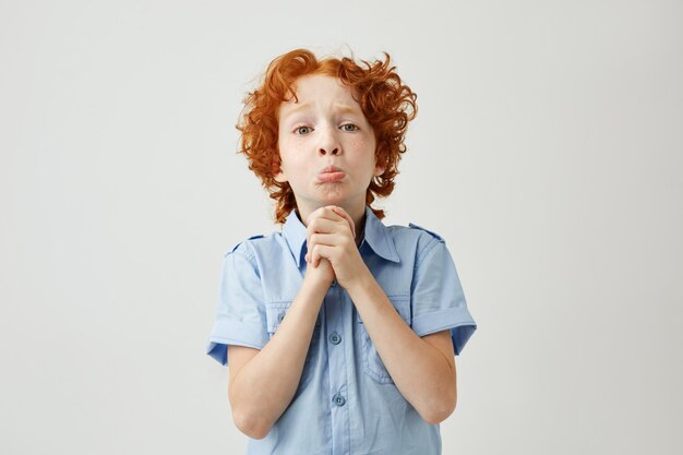 Funny ginger boy with sad and guilty face expression trying apologizes