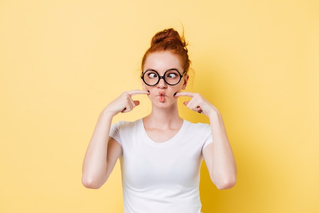 Funny ginger woman in eyeglasses puffed-off cheeks