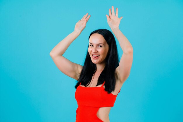 Funny girl is dancing by raising up her hands on blue background