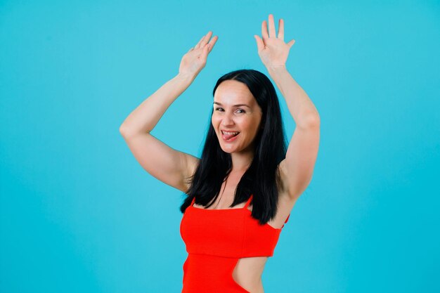 Смешная девушка танцует, подняв руки на синем фоне