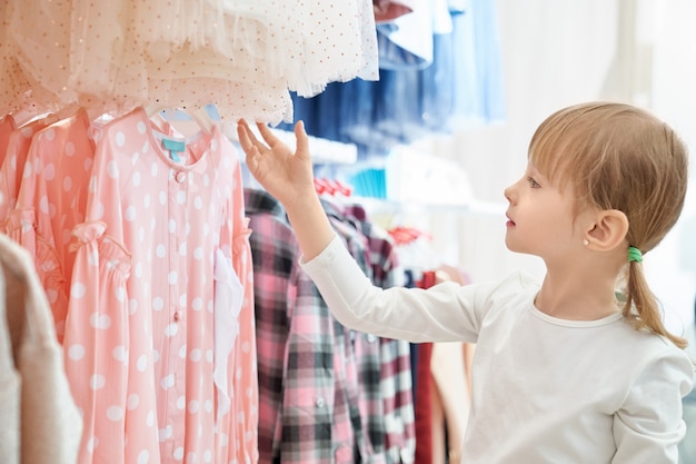 Funny girl looking at lovely pink dress in store