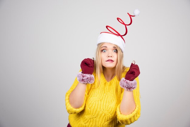 Funny girl in a yellow sweater and Santa's hat posing.