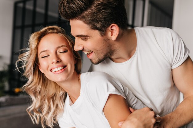 Funny guy chilling at home with girlfriend. Indoor portrait of smiling couple.
