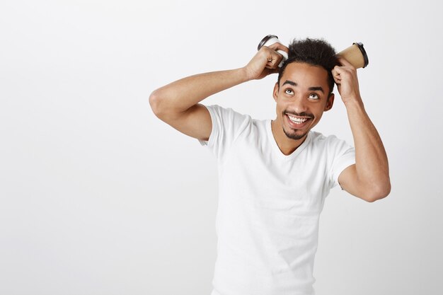 Funny handsome african american guy playing with paper cups and smiling broadly