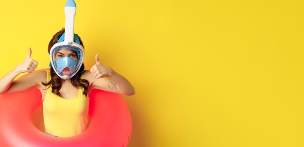 Free photo funny happy woman in swimming ring wearing snorkling mask for diving showing thumbs up good approval