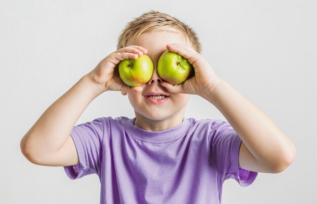 Funny kid holding green apples