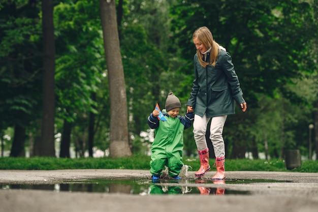 Funny kid in rain boots playing in a rain park