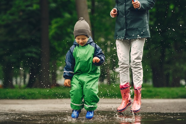 Foto gratuita bambino divertente in stivali da pioggia che giocano in un parco di pioggia