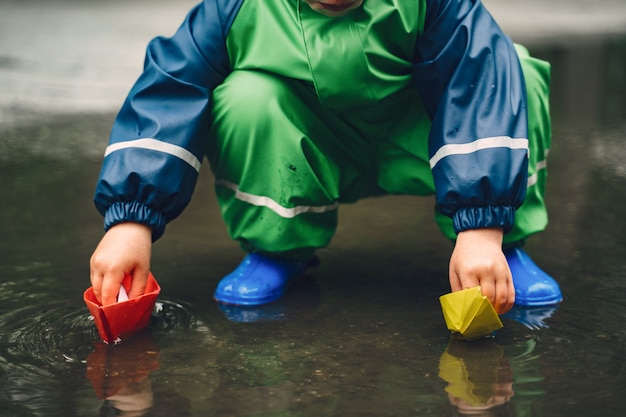 Foto gratuita bambino divertente in stivali da pioggia che giocano in un parco di pioggia