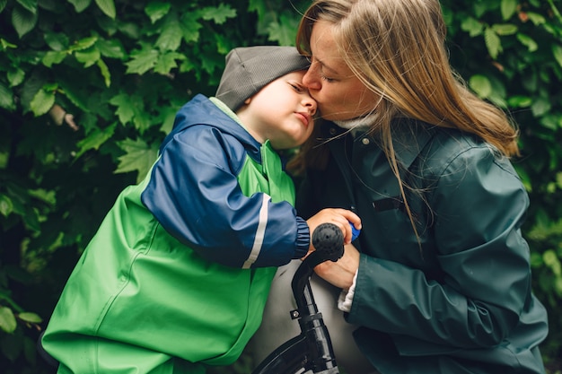 Bambino divertente in stivali da pioggia che giocano in un parco di pioggia