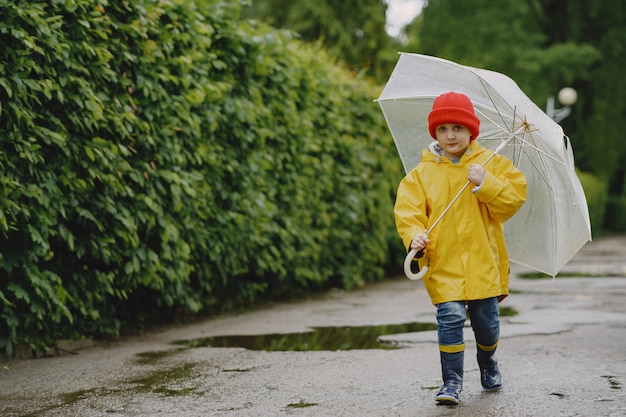 Funny kids in rain boots playing by a puddle