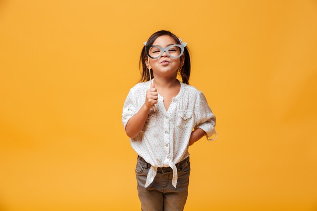 Funny little girl child holding fake glasses.