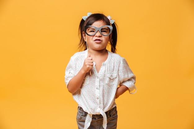 Funny little girl child holding fake glasses.