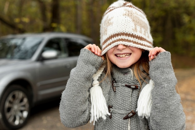 Смешная маленькая девочка закрыла лицо зимней шапкой