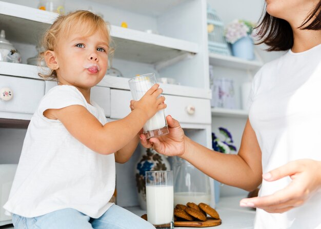 Смешная маленькая девочка держит стакан молока