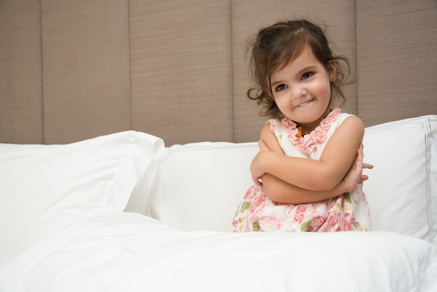 Free photo funny little girl hugging self in bed