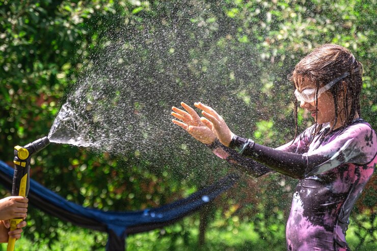 無料Photo 陽気な裏庭で庭のホースで遊ぶ面白い小さな女の子