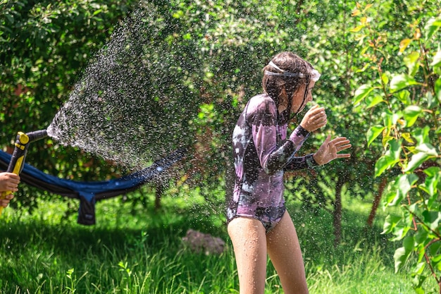 Foto gratuita bambina divertente che gioca con il tubo da giardino nel cortile soleggiato