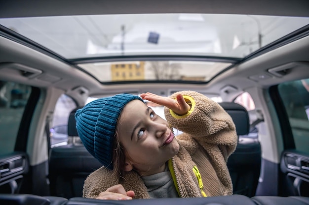 Free photo funny little girl posing in the back seat of a car playing in the car