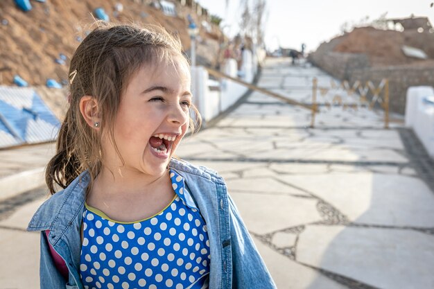 A funny little girl saw something interesting in the distance and laughing.