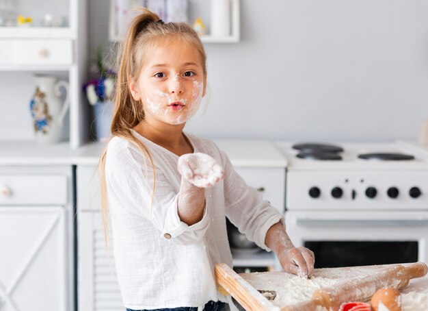 Funny little girl showing her hand with flour