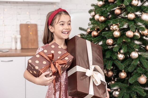 Funny little girl with gift boxes near the christmas tree