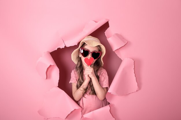 funny little girl with a heart on a stick on a colored background