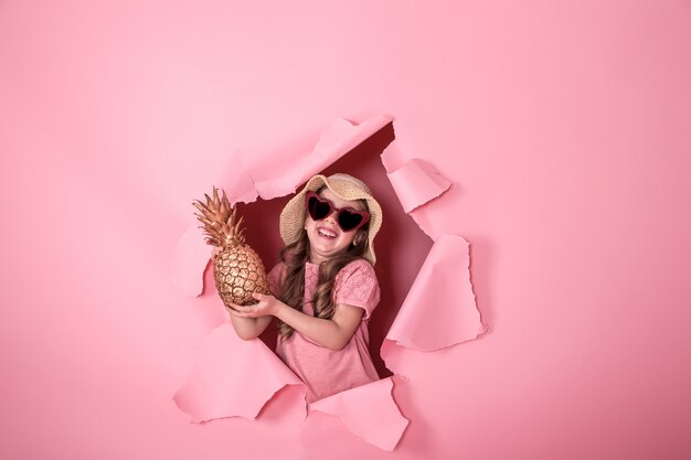 Funny little girl with pineapple on colored background