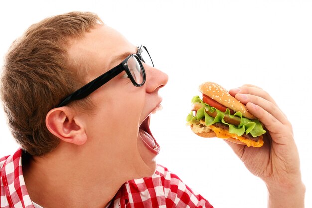Foto gratuita uomo divertente in vetri che mangia hamburger isolato su un bianco