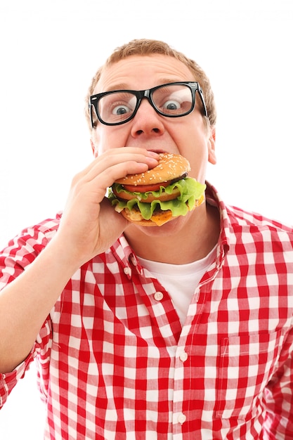 Смешной человек в очках ест гамбургер, изолированных на белом