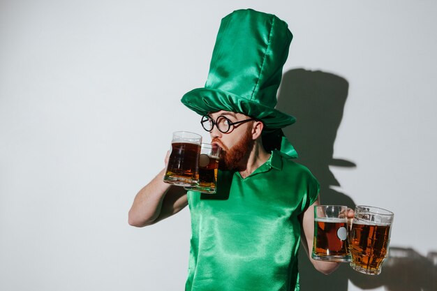 Funny man in st.patriks costume drinking beer from two cups