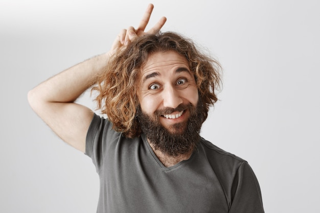 Free photo funny middle-eastern bearded man smiling and showing horns up above head