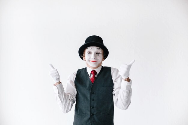 黒い帽子の面白いmimeは彼の親指を保持する