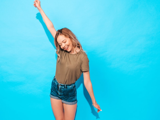 Free photo funny model posing near blue wall in studio.raises her hands