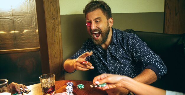 Funny photo of friends sitting at wooden table. Friends having fun while playing board game.