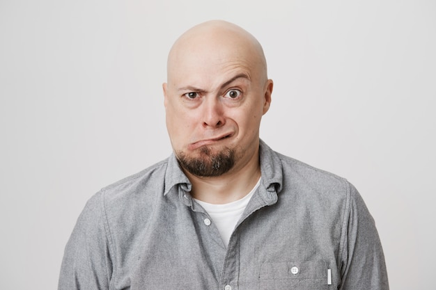 Free photo funny playful bald adult man squinting and grimacing