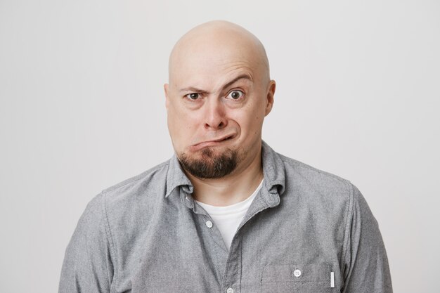 Funny playful bald adult man squinting and grimacing