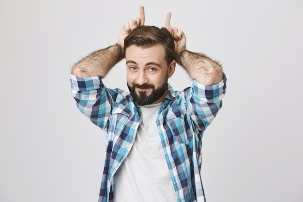 Free photo funny playful bearded man making devil horns gesture