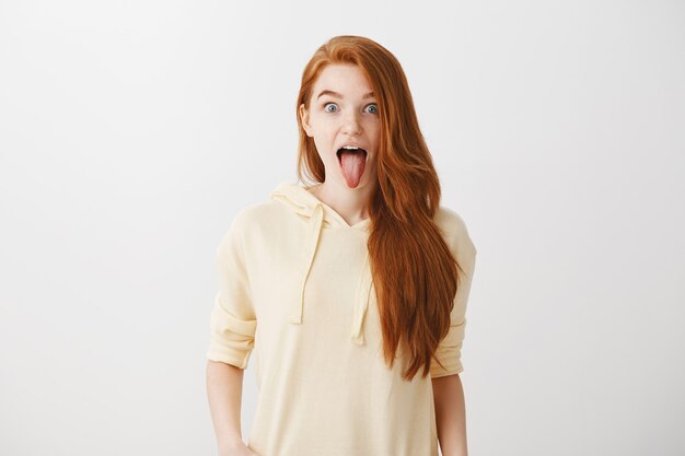 Funny playful redhead girl showing tongue and looking excited