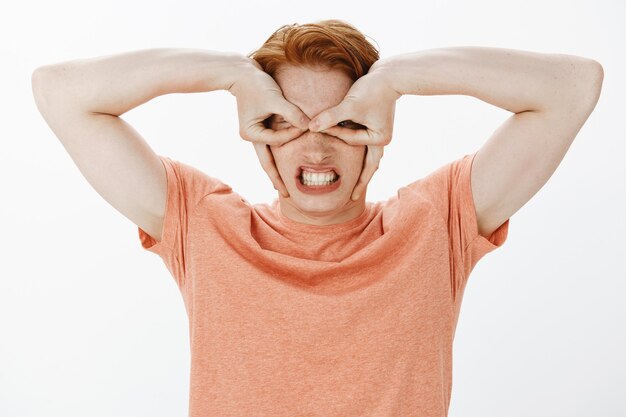 Funny and playful redhead man acting like superhero, making hero mask with hands