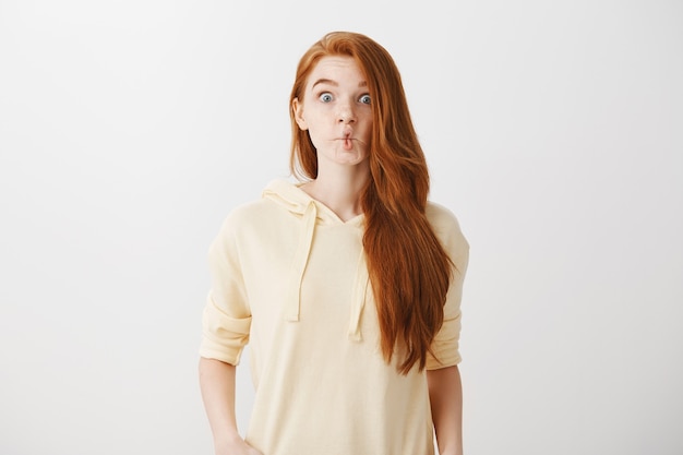 Free photo funny redhead girl sucking lips like fish, grimacing