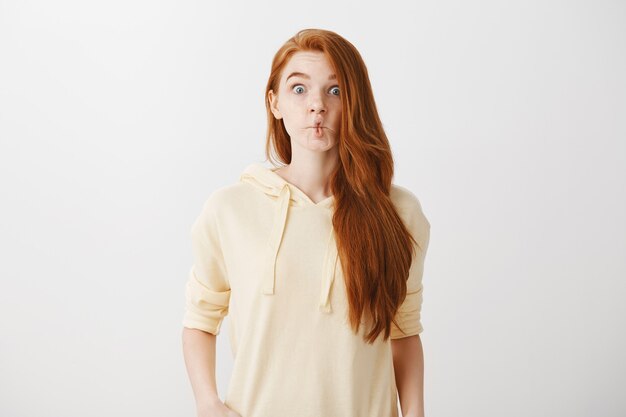 Funny redhead girl sucking lips like fish, grimacing