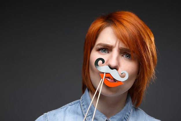 Funny redhead woman wear fake moustache and lips