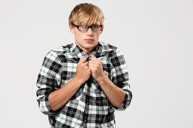 Funny scared blond handsome young man wearing casual plaid shirt looking at camera copy space over grey background