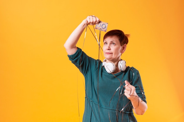 Free photo funny senior woman looking at a cassette tape