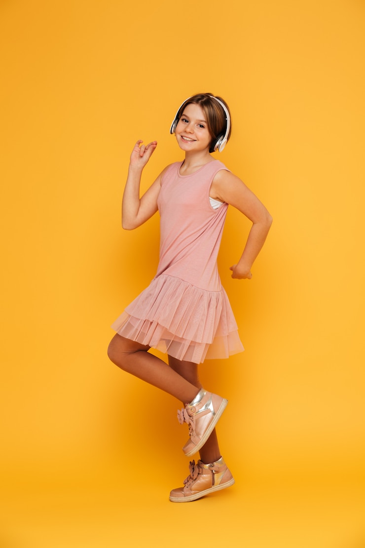 Free Photo funny smiling girl in headphones dancing isolated over yellow